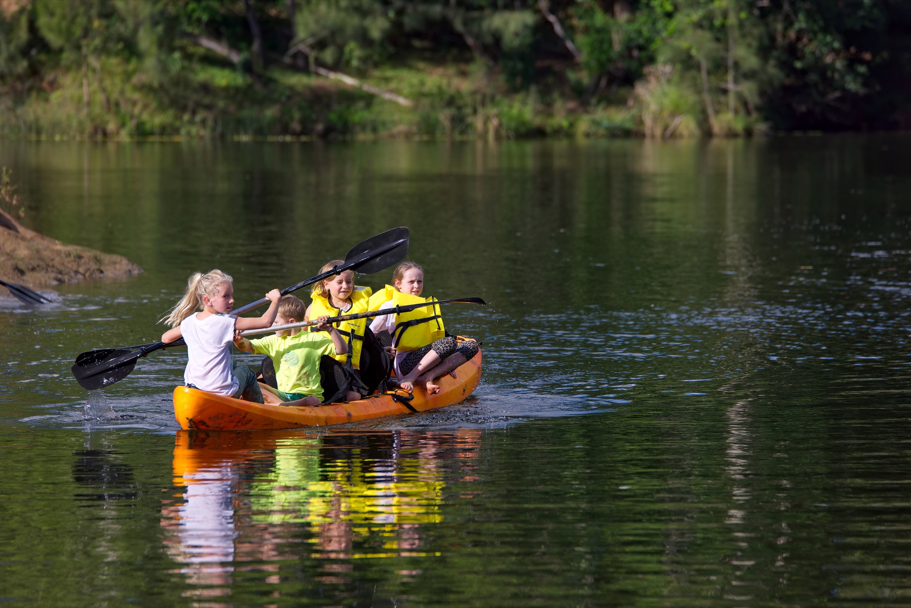 Children paddling an orange kayak together on Yabba Creek