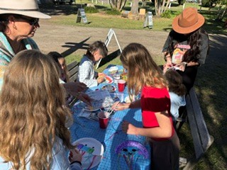 Children making colourful jellyfish crafts at an outdoor camp table