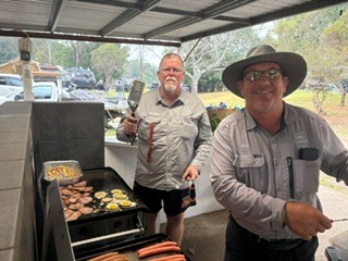 Two cooks preparing bacon and eggs on the campground barbecue